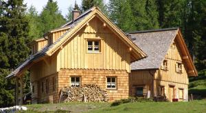 een houten huis met een stapel houtblokken bij Schermerhütten in Tauplitzalm