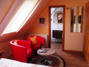 Habitación con sillas rojas, mesa y ventana en Gästehaus Ziemann, en Friedrichstadt
