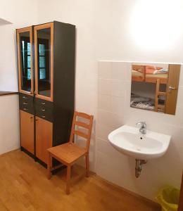 a bathroom with a sink and a wooden chair at Dom Pristava in Jesenice