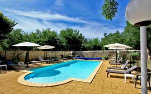 a swimming pool with patio furniture and umbrellas at Hôtel Restaurant Le Relais des Gourmands in Gramat