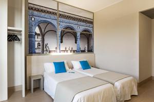 twee bedden in een kamer met een muurschildering van een gebouw bij B&B Hotel Firenze Nuovo Palazzo Di Giustizia in Florence