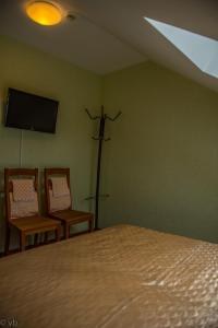 a bedroom with a bed and two chairs and a tv at Prie upes in Kunioniai