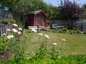un jardín con un cobertizo rojo y algunas flores en Eypeleaze B&B en Bridport