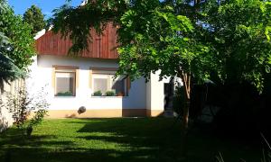 una casa con 2 ventanas y un patio verde en Júlia Vendégház Sarród en Sarród