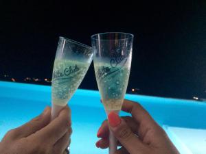 Zwei Hände mit zwei Gläsern Champagner in der Unterkunft White Club Residence in Belvedere Marittimo