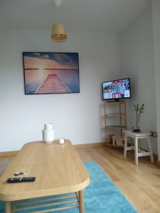 een woonkamer met een houten tafel en een televisie bij Apartamento Camiño dos Faros in Ponteceso