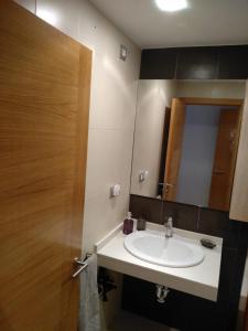 baño con lavabo y puerta de madera en Apartamento Camiño dos Faros, en Ponteceso