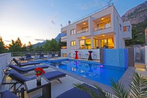 a villa with a swimming pool in front of a house at Villa Inis in Makarska