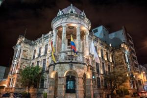 un edificio con banderas por la noche en Hotel La Orquidea en Cuenca