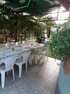 a long table with white tables and white chairs at Green House in Nea Peramos