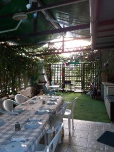 a long table with white chairs in a garden at Green House in Nea Peramos