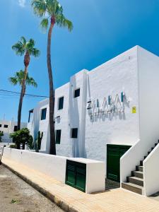 a white building with two palm trees in front of it at Apartamentos Zalabar in Tías