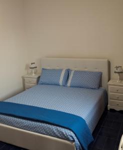 a bedroom with a bed with blue sheets and two night stands at B&B Il Villino in Torre dell'Orso