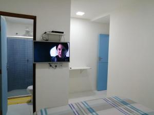 a bathroom with a tv on a wall in a room at Suítes Da Vila 152 in Praia do Forte