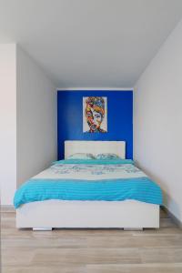 1 dormitorio con 1 cama con pared azul en Luxury Olimpia Studio in Bucharest, with Netflix, en Bucarest