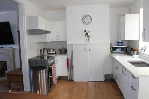 una cocina con armarios blancos y un reloj en la pared en Walmer House en Deal