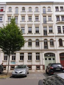 ein großes weißes Gebäude, vor dem Autos parkten in der Unterkunft Ferienwohnung Busch in Leipzig