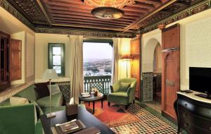 un salon avec un canapé vert et une télévision dans l'établissement Palais Faraj Suites & Spa, à Fès