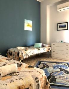 two beds in a room with blue walls and a rug at Casa Aurora in Catania