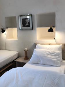 a bedroom with two beds with white sheets and two lights at Masseria Croce Piccola - Wineyard in Martina Franca