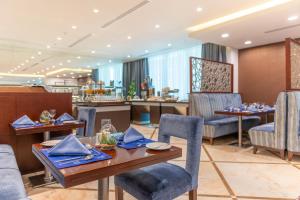a dining room with tables and chairs and a bar at Century Hotel Doha in Doha