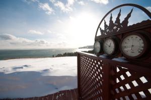 un reloj en una valla con nieve y el océano en Domaine Frais Air, en La Malbaie