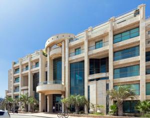 duży budynek z palmami przed nim w obiekcie Lagoon Water Front Garden Patio w mieście Herzliya