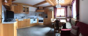cocina con armarios de madera, mesa y TV en Biobergbauernhof Bergzeit Apartment in Goldegg, en Goldegg