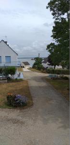 un camino vacío con flores al lado de una casa en Au calme, les pieds dans l'eau, 106 Route de la Pointe de Ruault 56370 SARZEAU, en Sarzeau