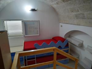 Habitación pequeña con sofá rojo y ventana en Casa Sosò, en Maruggio