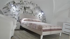 una camera bianca con un letto e carta da parati floreale di Casa Le Site a Palmariggi