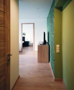 um corredor com um quarto com paredes verdes e uma televisão em Green leaf apartments em Liepāja