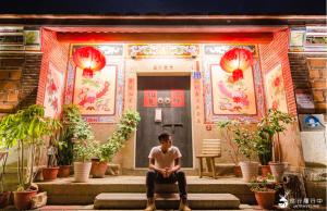 a man sitting on steps in front of a building at I-Shan B&B in Jincheng