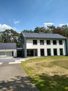 um grande edifício branco com um telhado preto em GOLF APARTMENT em Schilde