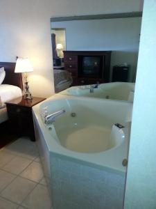 a large bath tub in a room with a bedroom at Days Inn by Wyndham Maumee/Toledo in Maumee