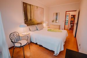 a bedroom with a white bed and a chair at Bela Vista in Viana do Castelo