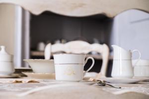stół z kubkami, talerzami i łyżką w obiekcie Villa Rambaudi w mieście Sanfrè