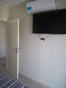 Habitación con pared blanca, TV y puerta. en Departamento Moderno Y Confortable en San Miguel de Tucumán