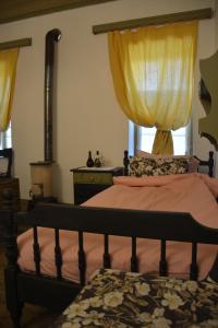 a bedroom with a bed and a window with yellow curtains at Casa di Cardellino in Psarades