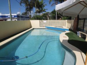 an empty swimming pool with an umbrella at Aspley Pioneer Motel in Brisbane