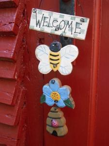 a door with a welcome sign and a bee and a flower at Ferienwohnung Villa Lütt in Bleckede