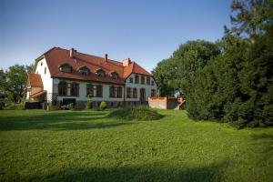 a large white house with a red roof on a green field at Pensjonat Myśliwski in Cedynia