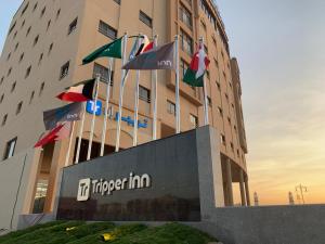 a hotel building with flags in front of it at Tripper Inn Hotel Apartments in Dammam