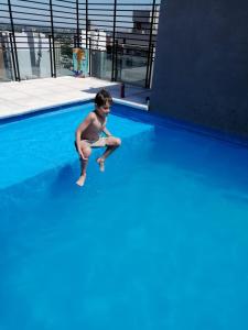 a young boy sitting on the edge of a swimming pool at Departamento Moderno Y Confortable in San Miguel de Tucumán