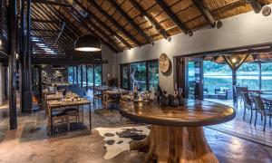 a restaurant with wooden tables and chairs and a large window at Kariega Game Reserve River Lodge in Kenton on Sea