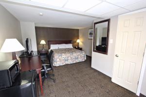 a hotel room with a bed and a desk and a television at Knights Inn Pine Grove I-81 Exit 100 in Pine Grove