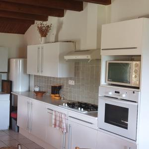 a kitchen with white cabinets and a microwave at Maisons du Père Paille in Usclades