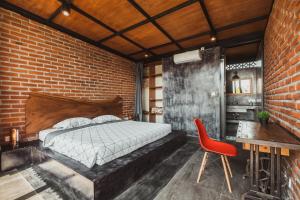 a brick walled bedroom with a bed and a red chair at Big Brother Berawa Beach in Canggu
