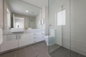 a bathroom with a toilet and a glass shower at Astra Apartments Newcastle (Merewether) in Merewether