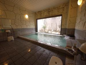 ein Bad mit einem Pool und einem Fenster in der Unterkunft Hotel Route-Inn Court Yamanashi in Yamanashi